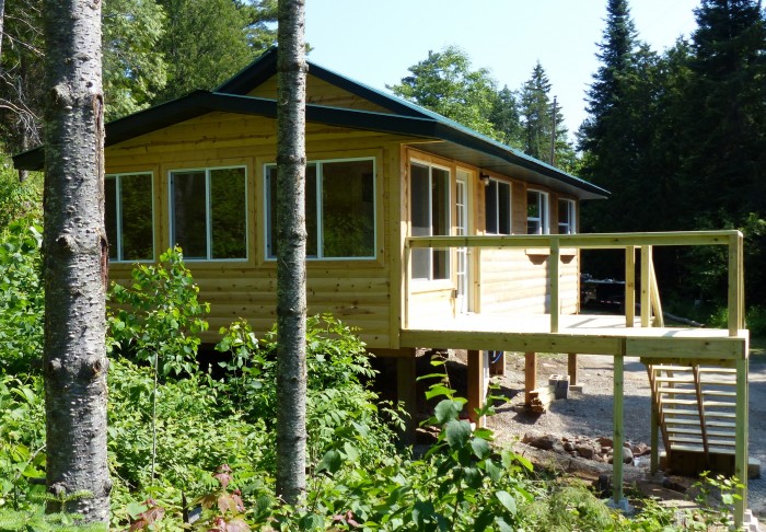 The windows of the 3 season room cover the corner of the cabin.